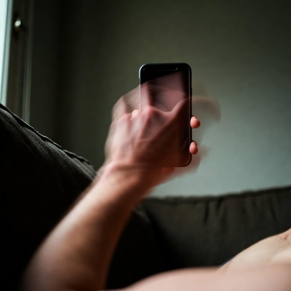 Shaky hand holding phone on couch at night