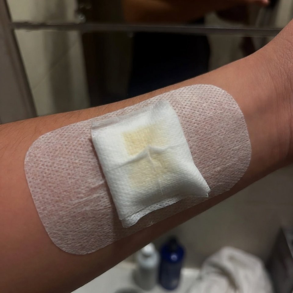 Forearm with fresh band-aid in dim bathroom mirror