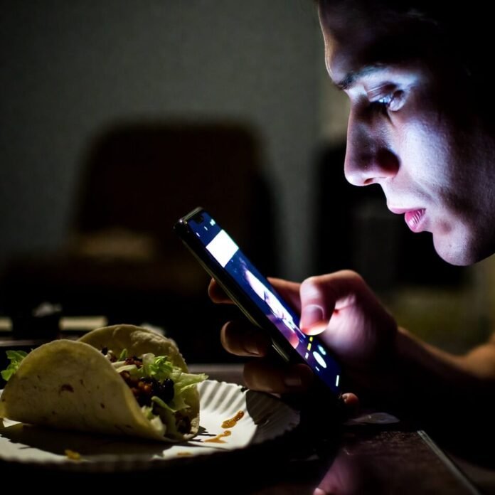 Late-night phone glow on unshaven face with taco