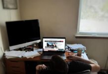 Breaking Business News: Companies Making Big Moves Slumped person staring at CNBC on laptop in messy office