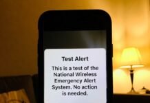 Health News Live: Outbreaks, Treatments & Wellness Trends Phone screen showing CDC alert in dim room with greasy takeout bag